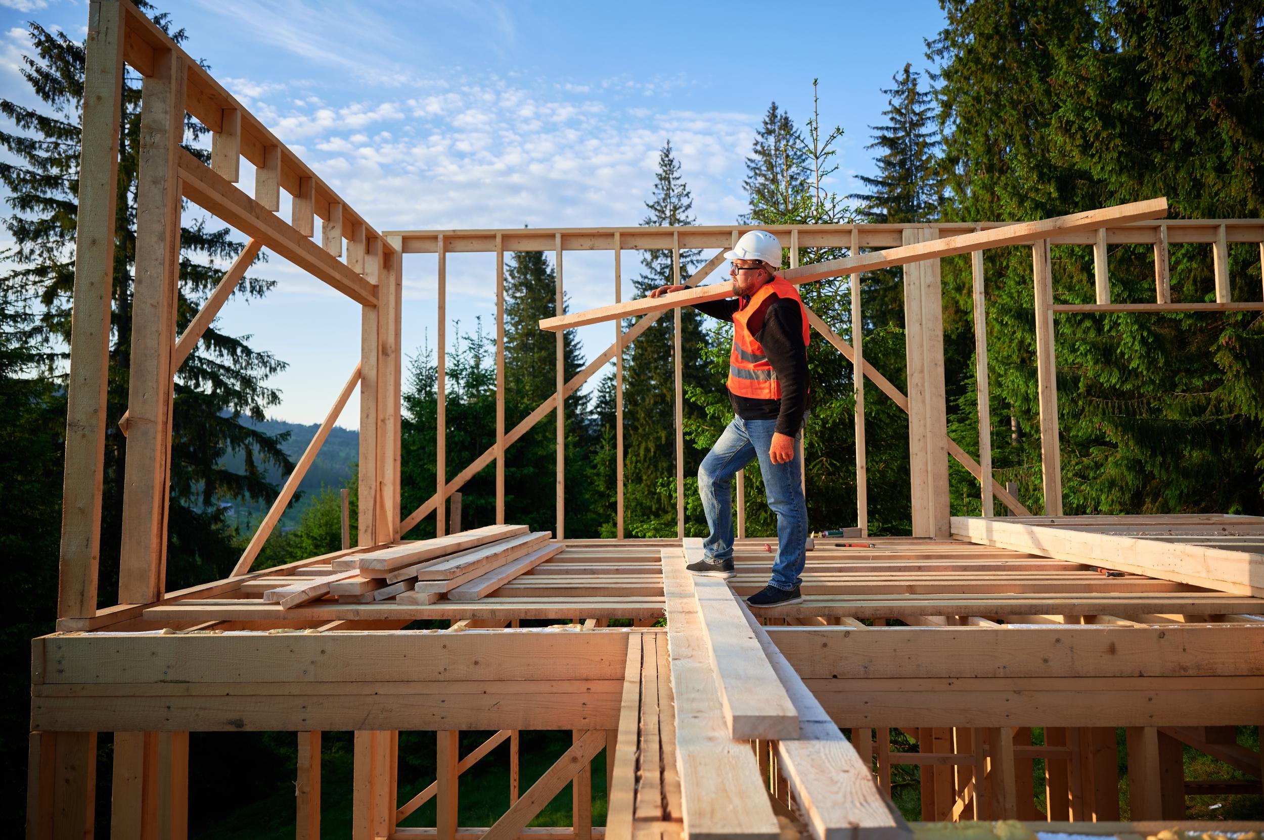 Carpenter,building,wooden Framed,house,near,the,forest.,man,holds,large